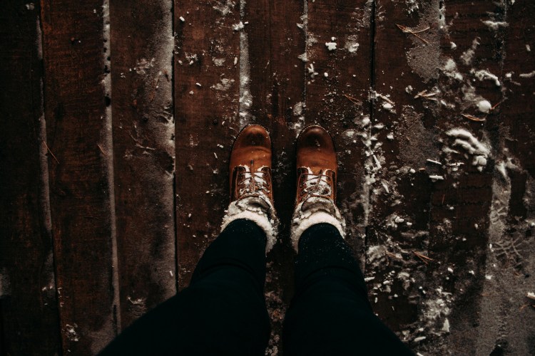 Woman in winter boots standing on brown wooden planks