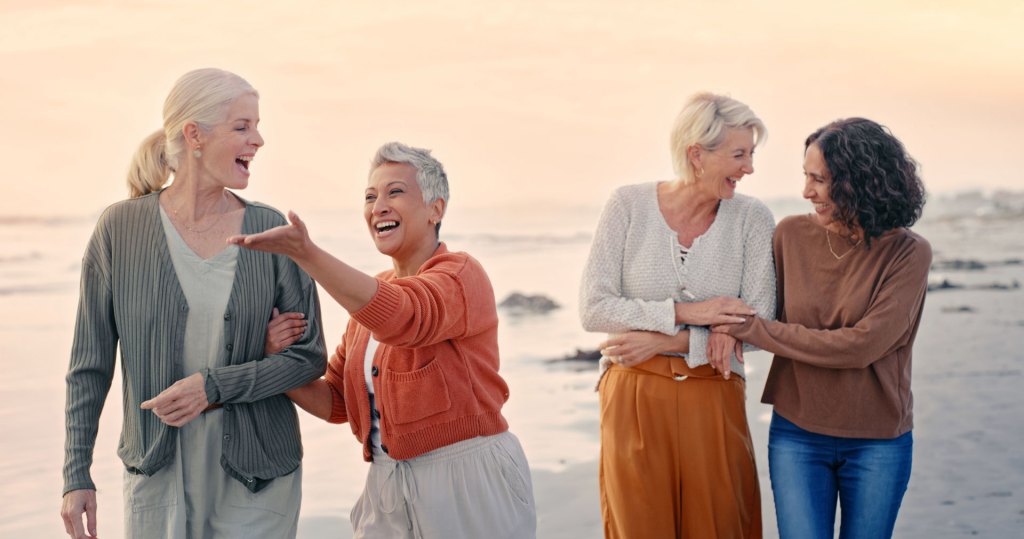 Group of women connecting over relaxed walk on the beach.
